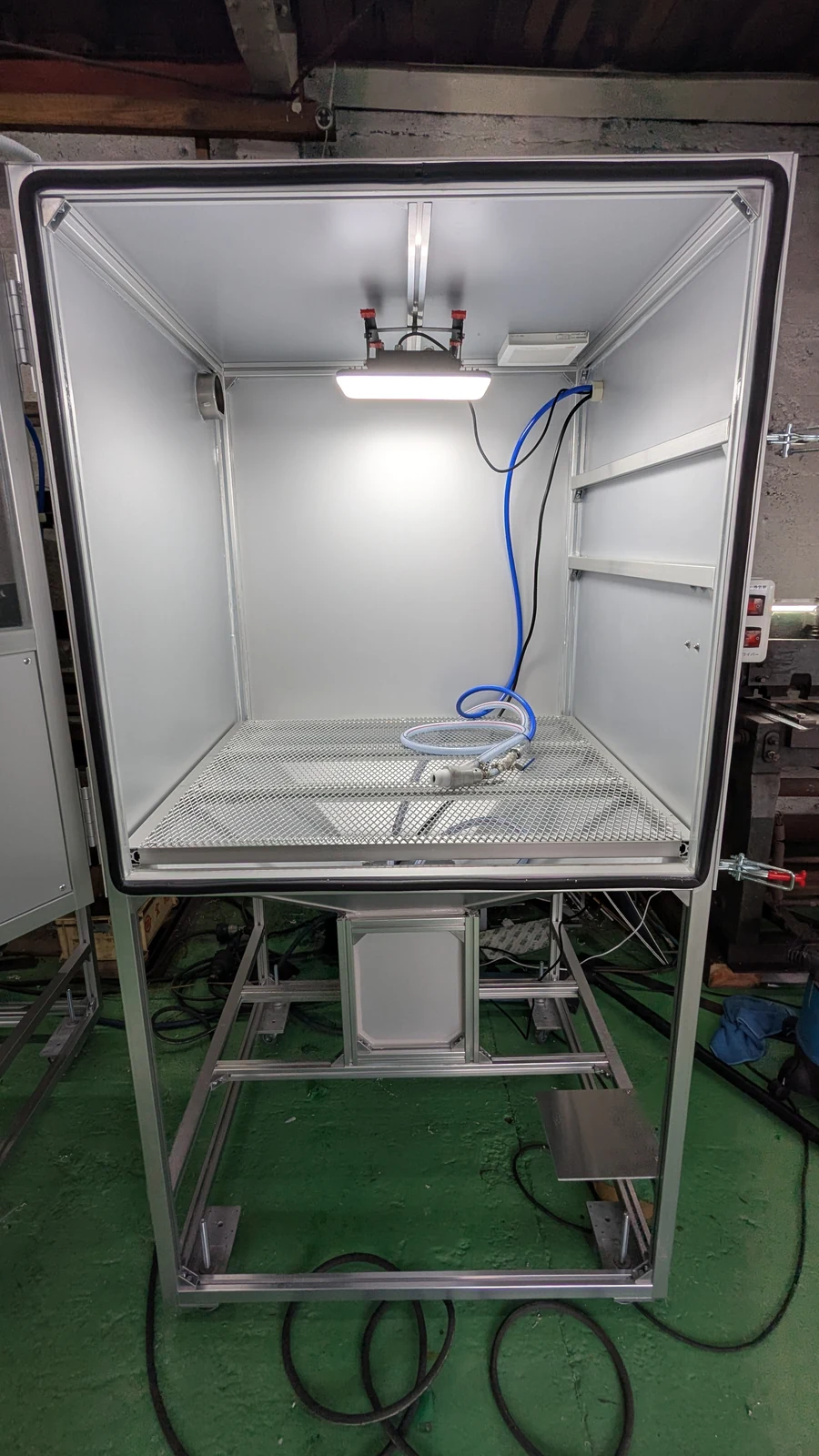 扉を開けた大型ウェットブラストマシンの作業室